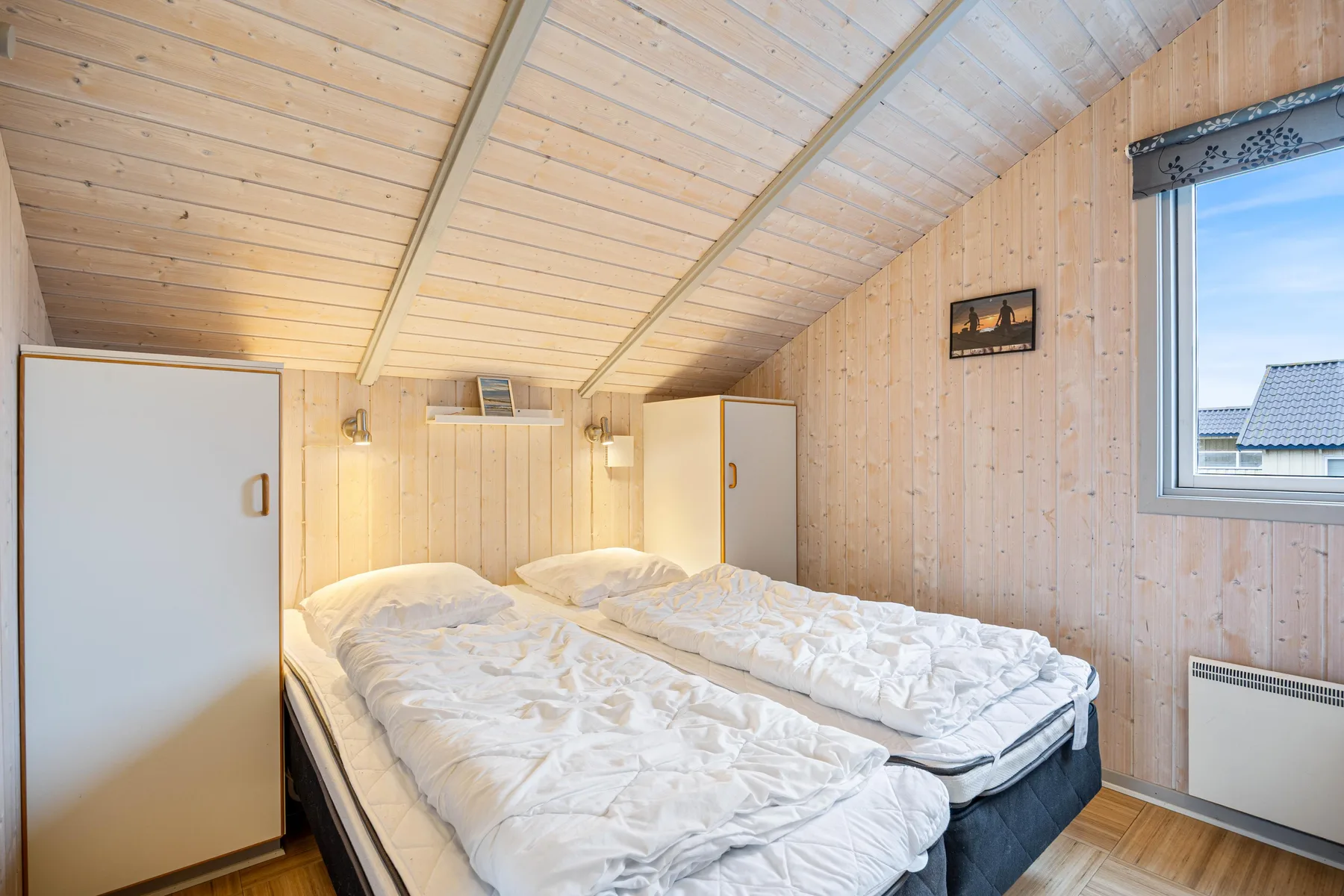 Un dormitorio con dos camas bajo un techo de madera inclinado.