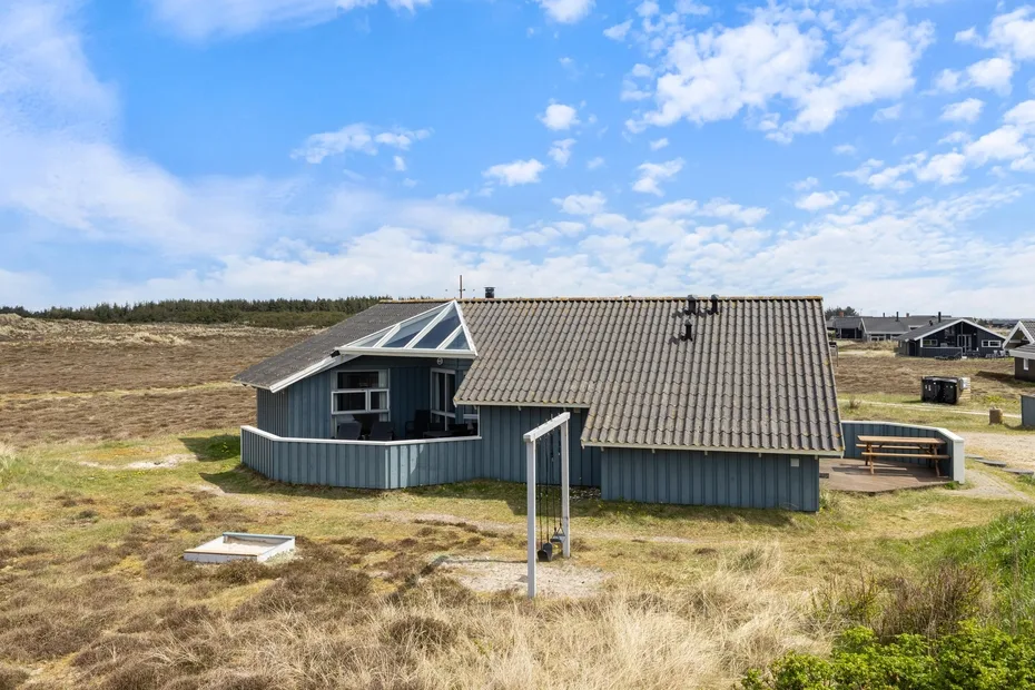 Una casa baja con techo inclinado se encuentra en un paisaje abierto de pastizales.