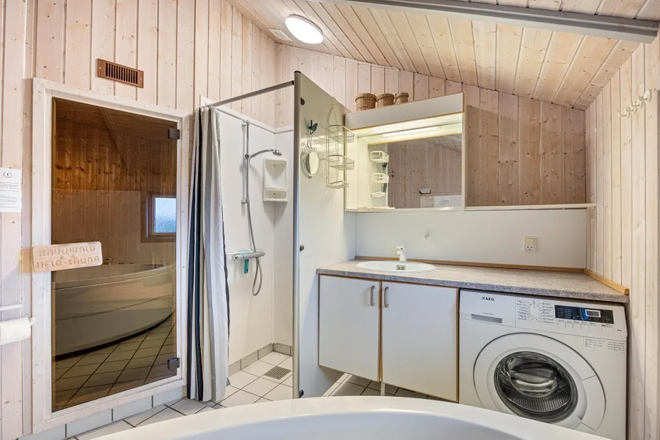 Un baño con ducha, lavabo y lavadora.