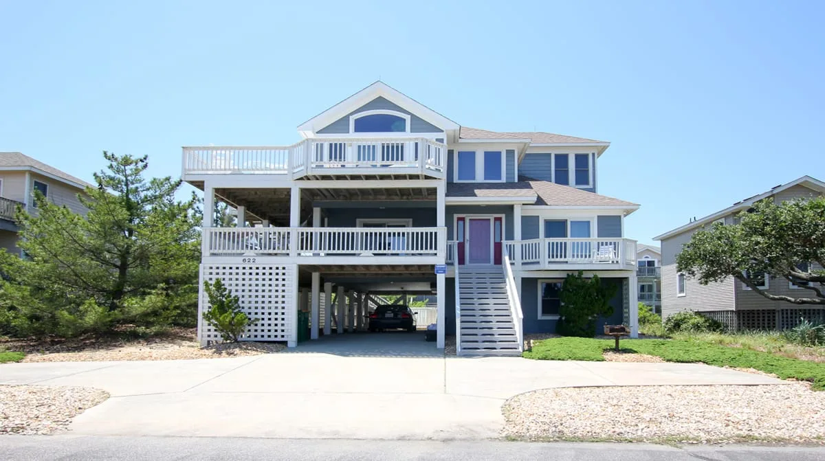 Una casa elevada con terrazas blancas y una escalera exterior.