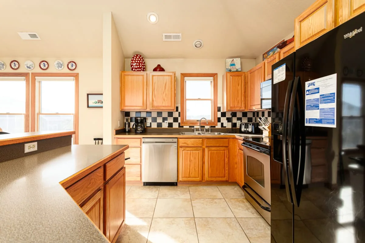 Una cocina luminosa con gabinetes de madera, encimeras de azulejos y una isla central.