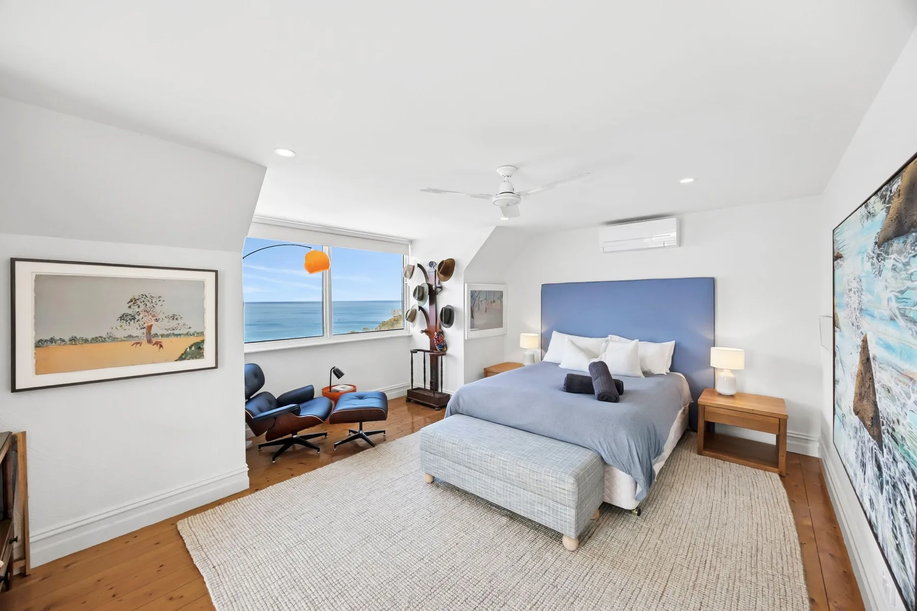 Un dormitorio luminoso con una cama, una zona de estar y vistas al mar por la ventana.