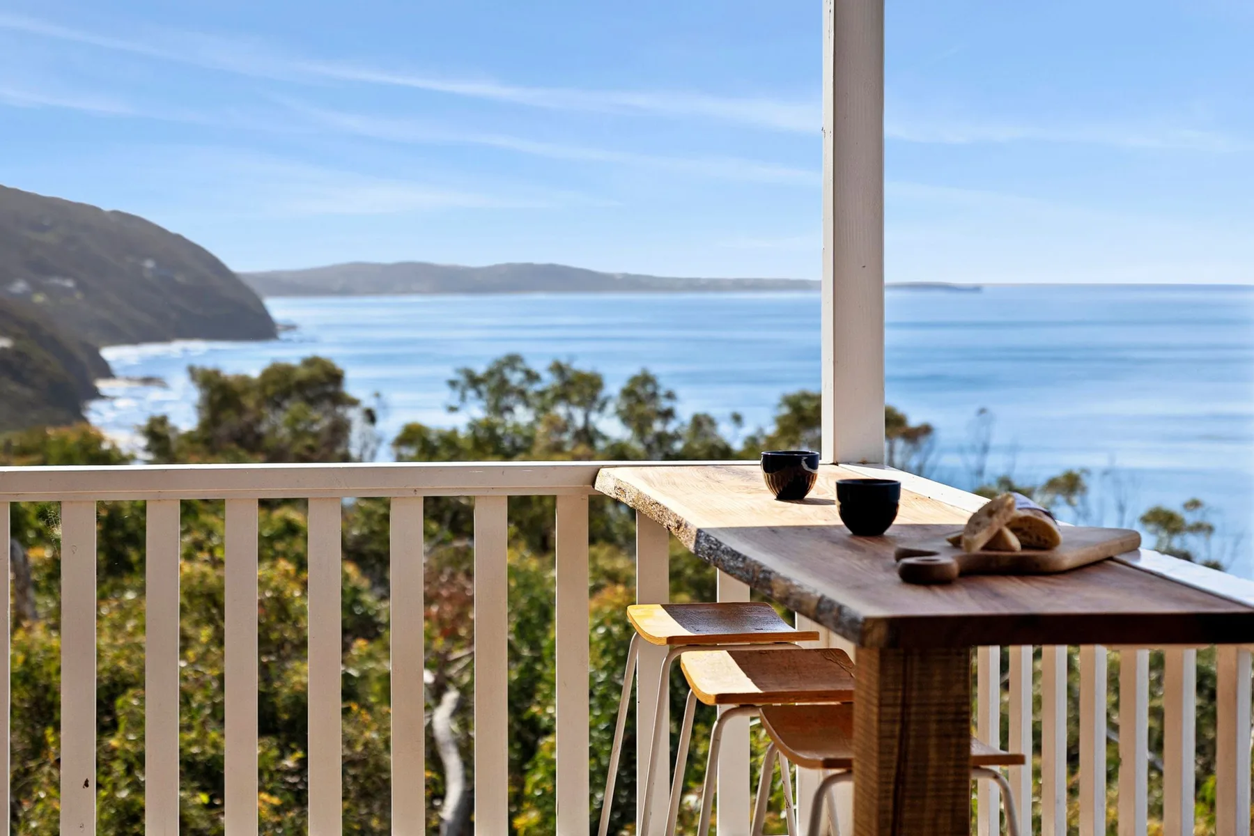 Una mesa de balcón tiene vistas al océano y a una costa lejana.