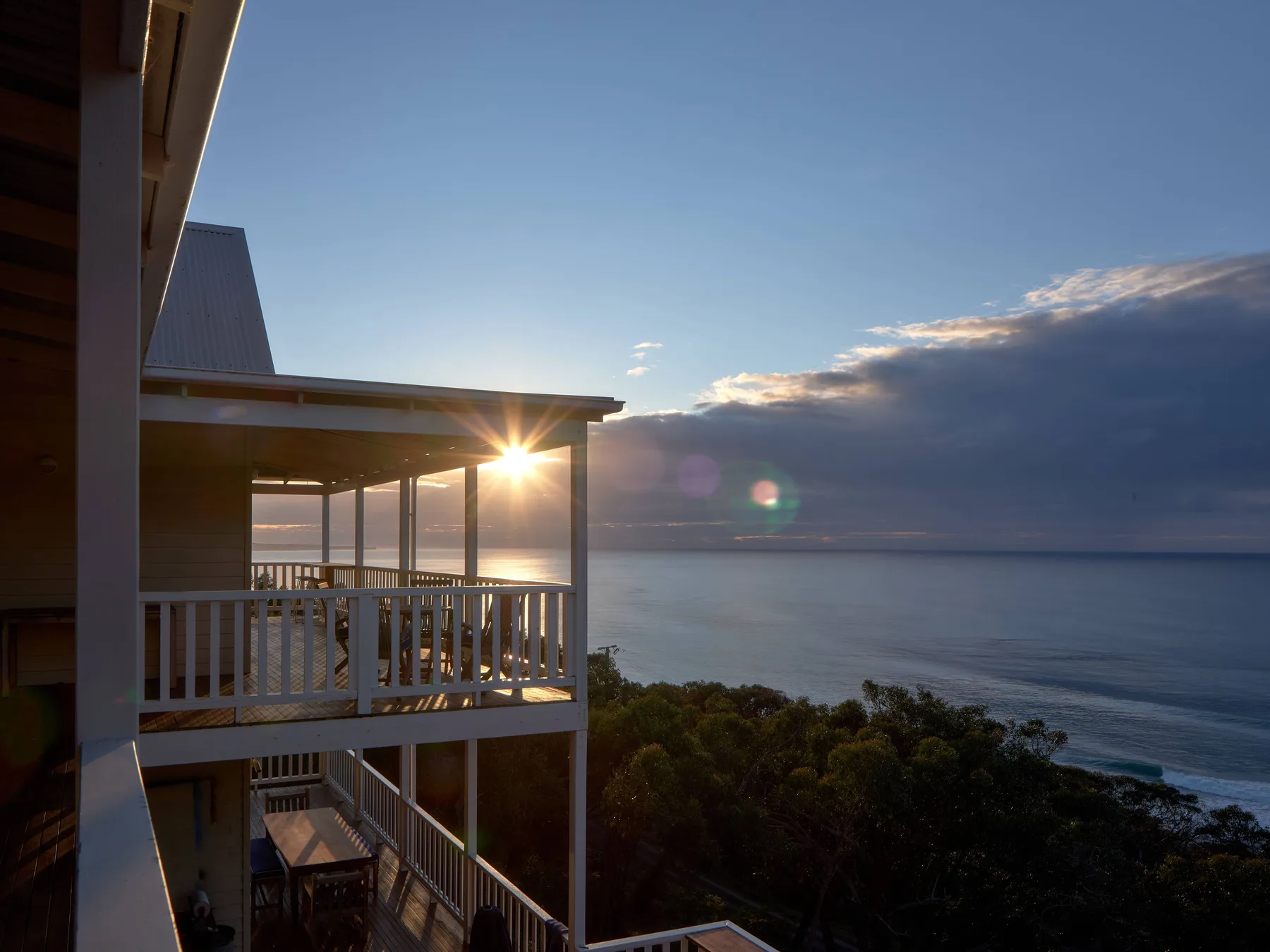 Una casa costera mira al océano al atardecer.