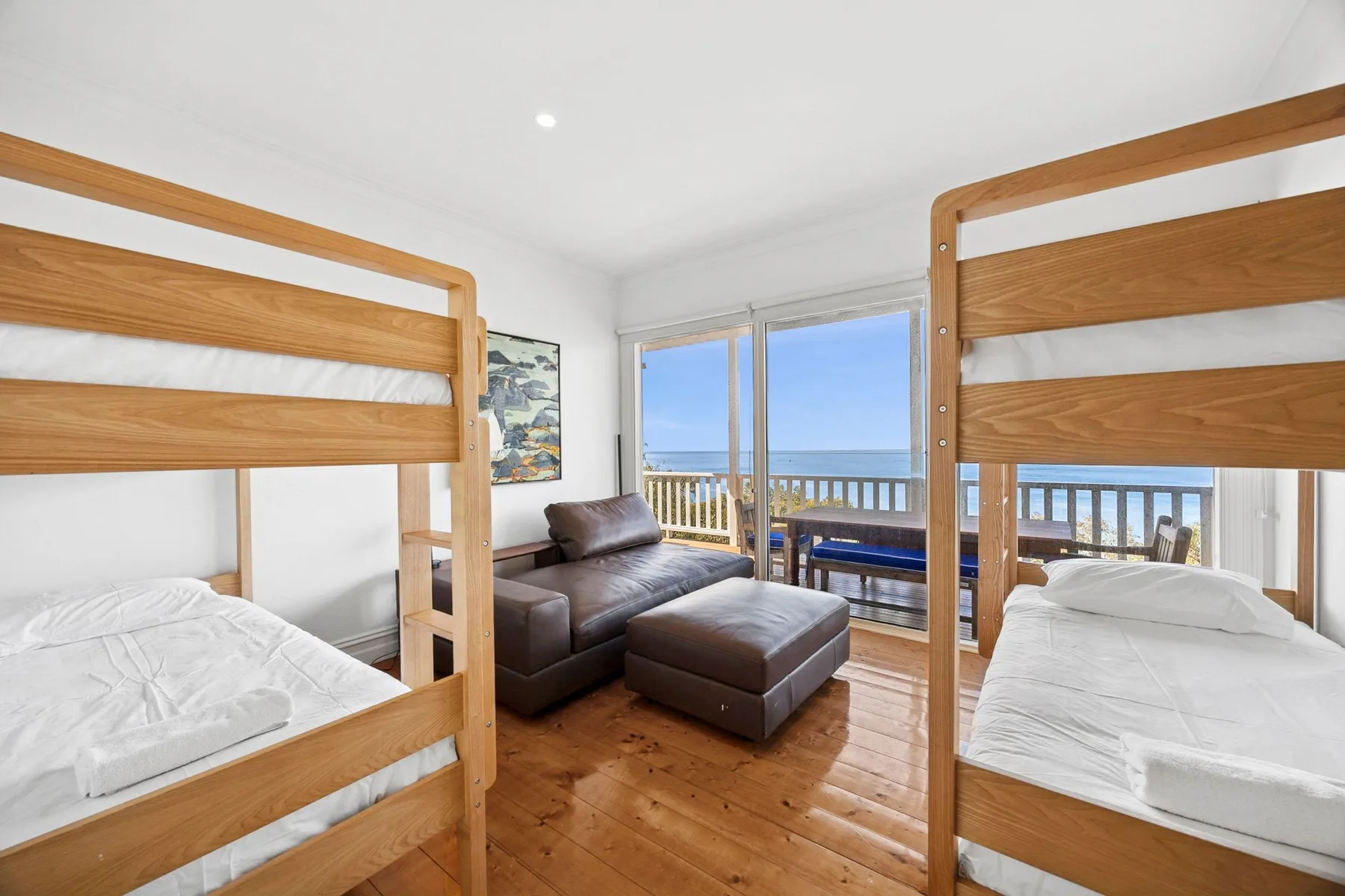 Un dormitorio con literas y asientos junto a ventanas con vistas al océano.
