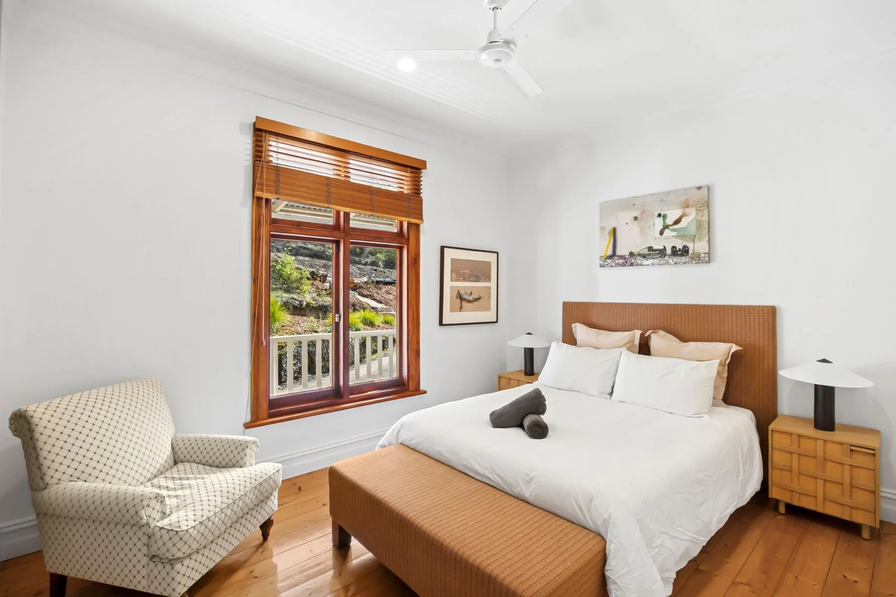 Un dormitorio luminoso con una cama bien tendida y una ventana con vistas a la vegetación.