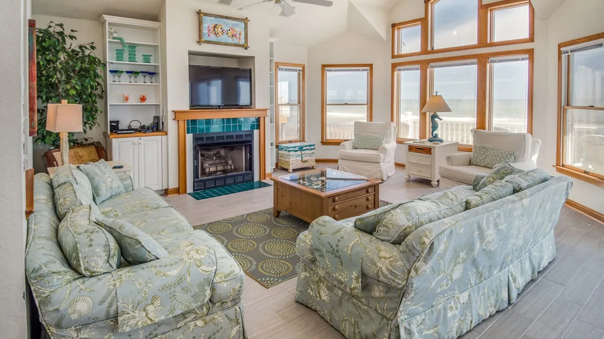 A bright living room with seating arranged around a coffee table and fireplace.