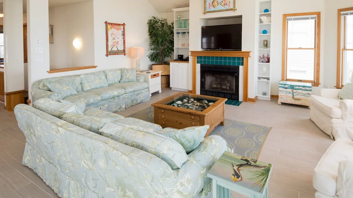 A living room with pale seating arranged around a coffee table and fireplace.
