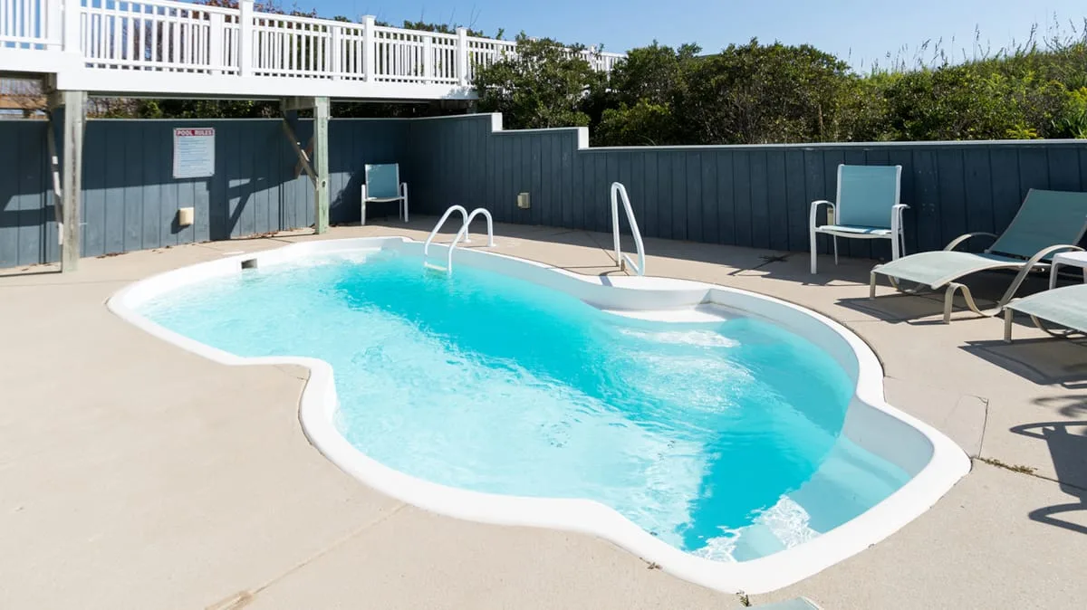 An outdoor swimming pool with lounge chairs on the surrounding deck.