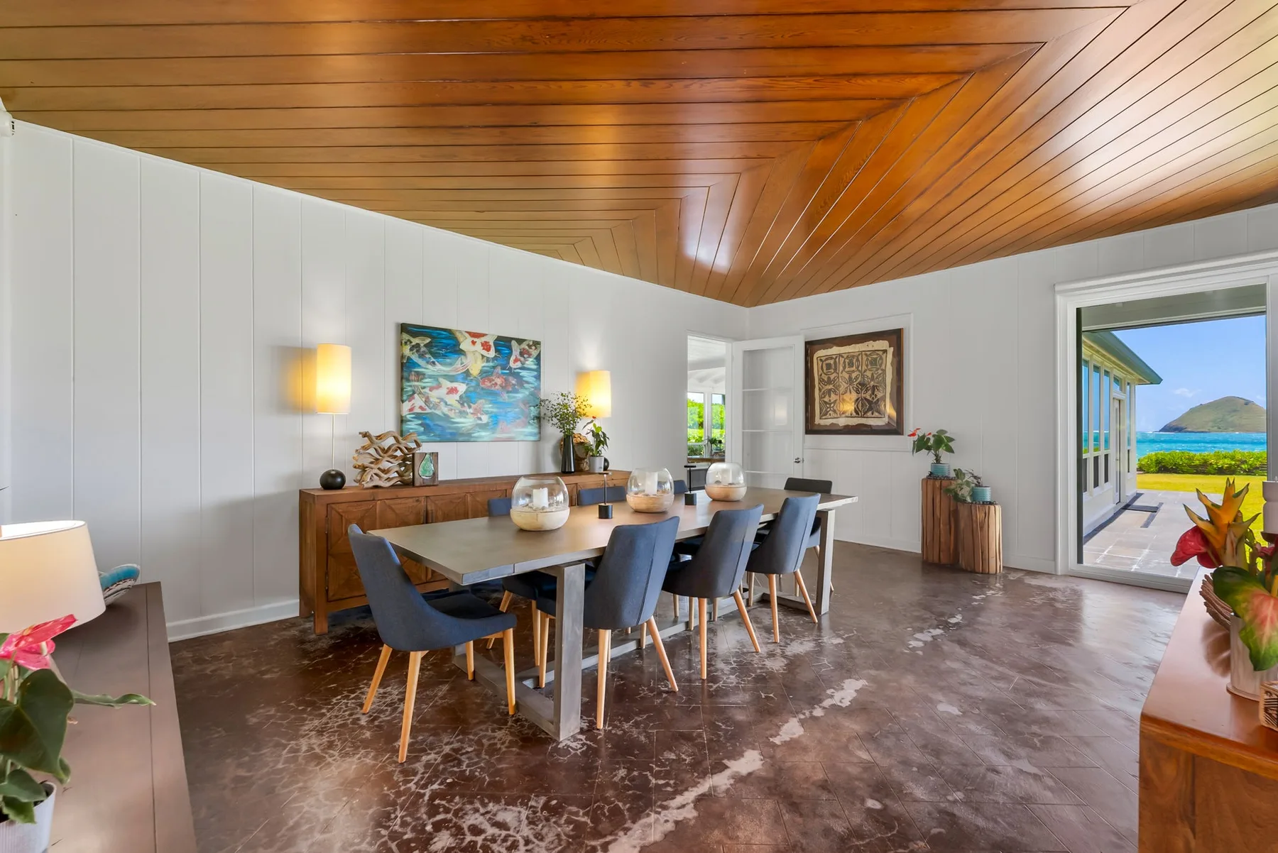 Un comedor con una mesa larga y sillas bajo un techo revestido de madera.