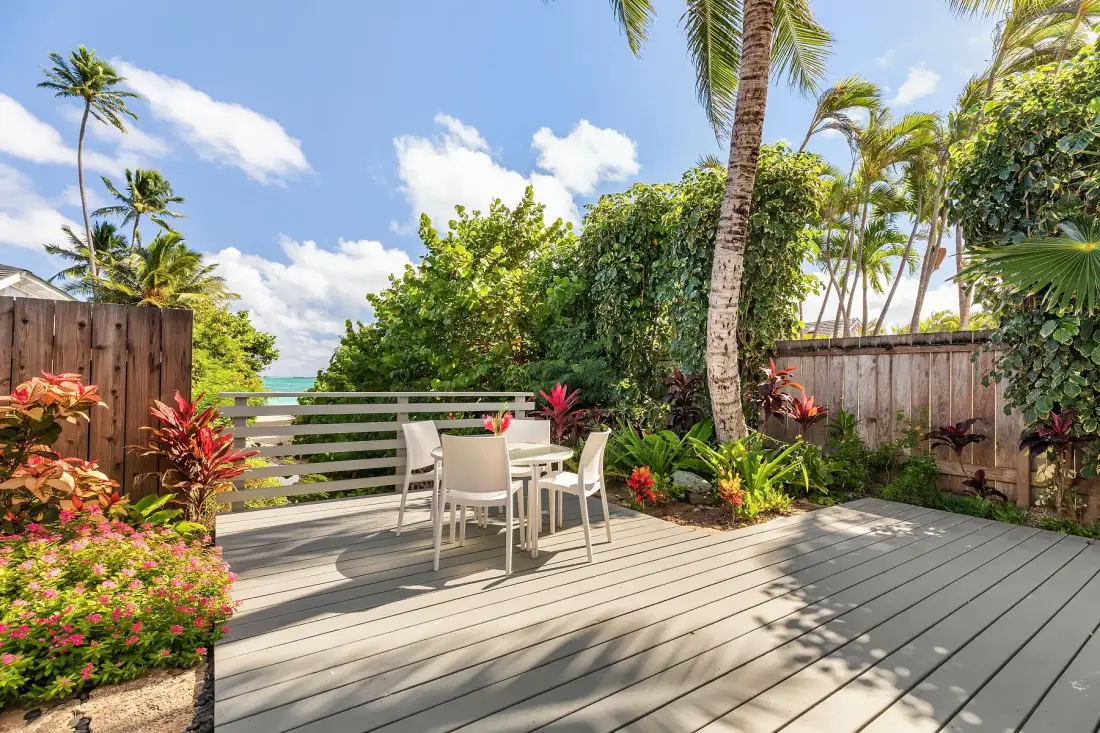 Una terraza exterior con una mesa y sillas, rodeada de plantas tropicales.