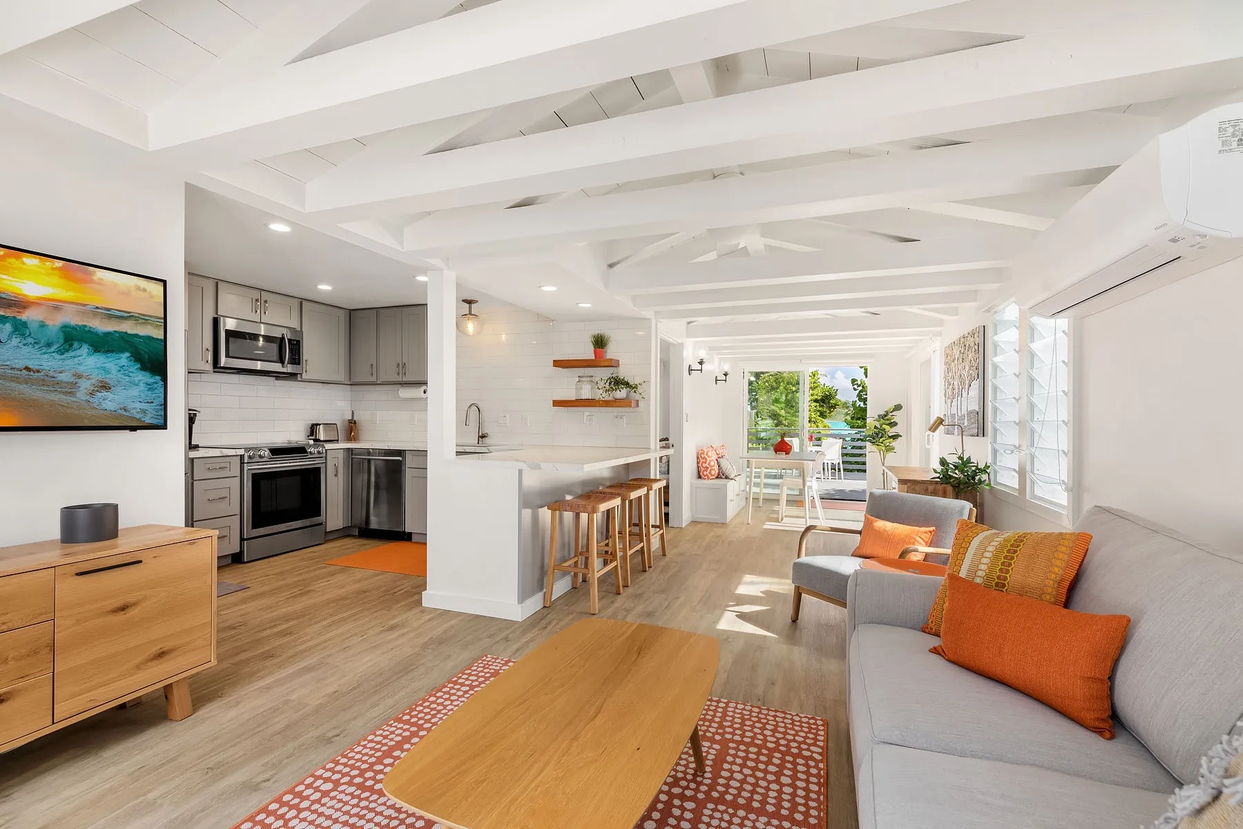 Una luminosa sala de estar y cocina de concepto abierto, con una barra para comer y asientos.