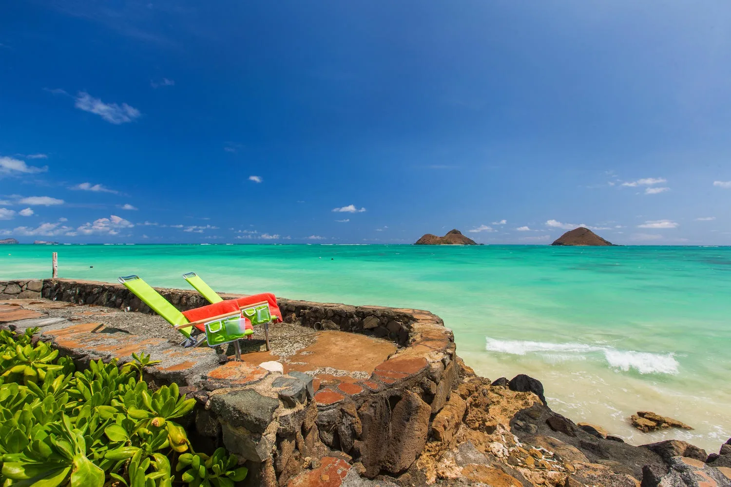 Una terraza rocosa junto al mar da a aguas turquesas y pequeñas islas.