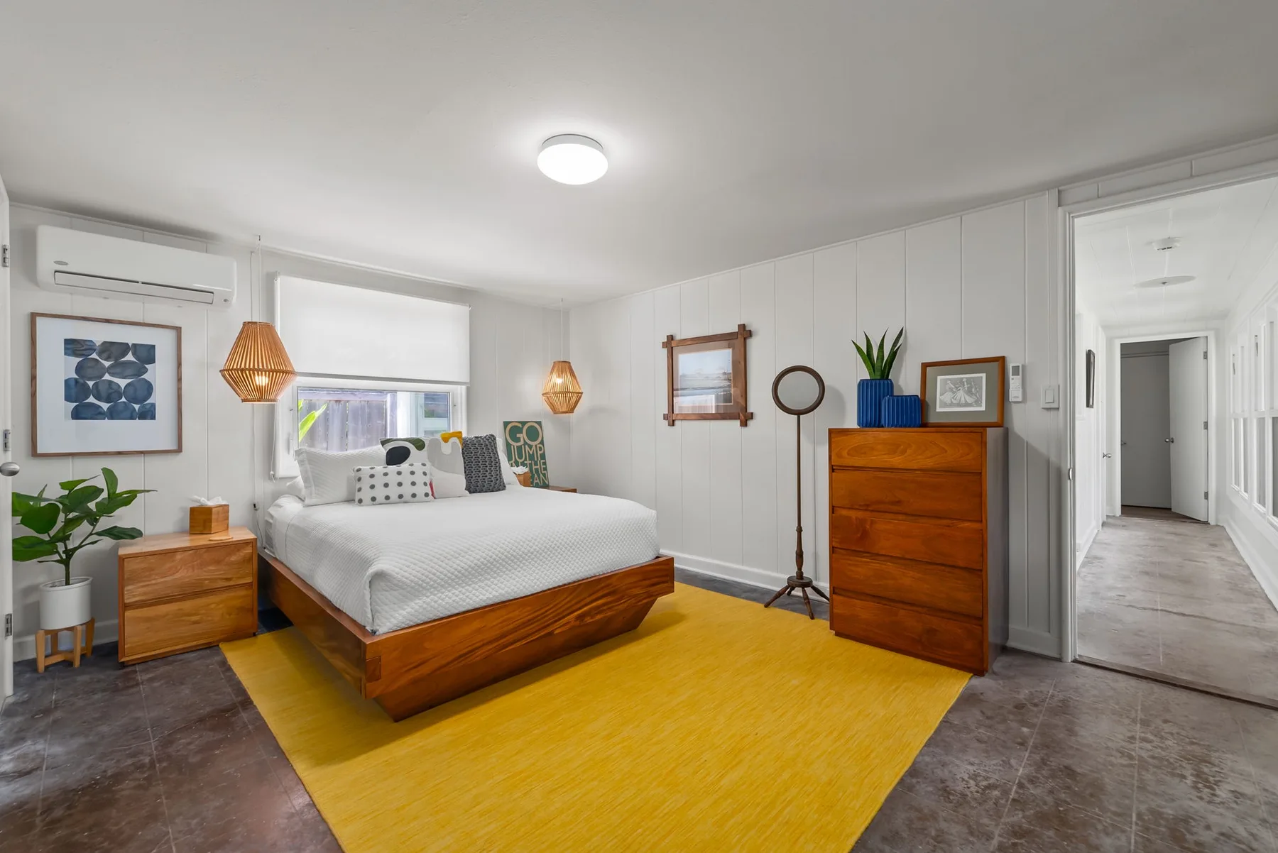Un dormitorio con una cama de madera, una alfombra amarilla y una cómoda a juego.