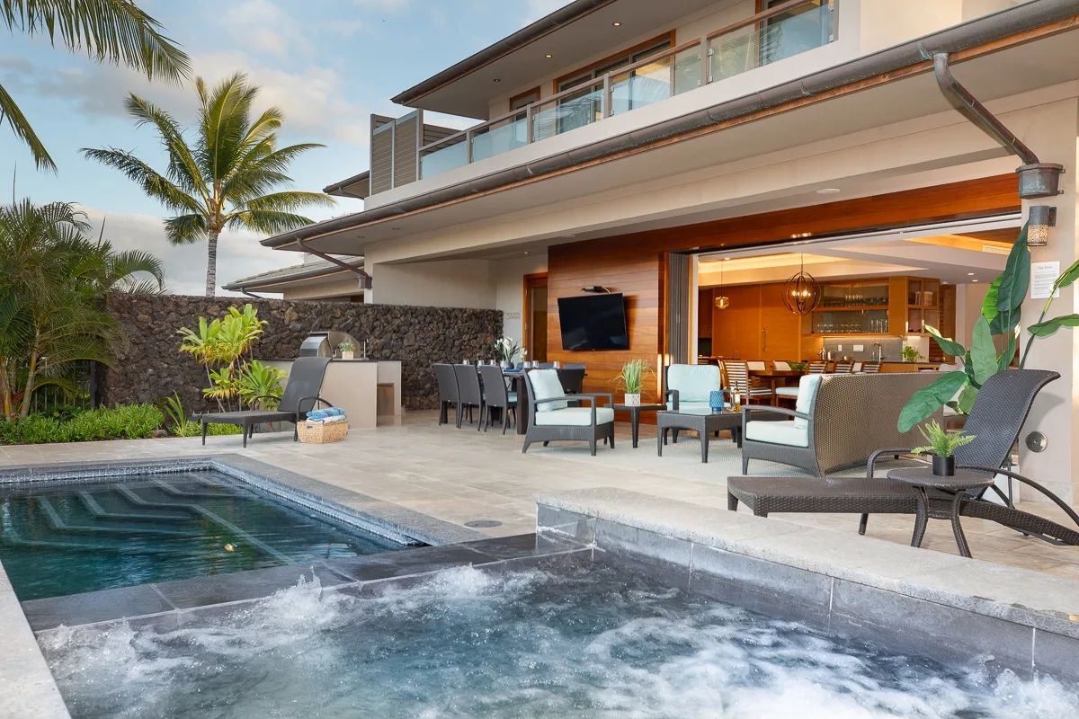 Un patio moderno se abre a una piscina, con asientos al aire libre junto al agua.