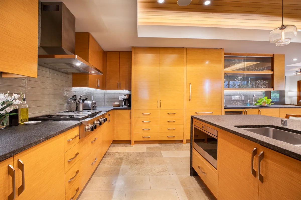 Una cocina amplia con gabinetes de madera, encimeras de piedra y una isla central.