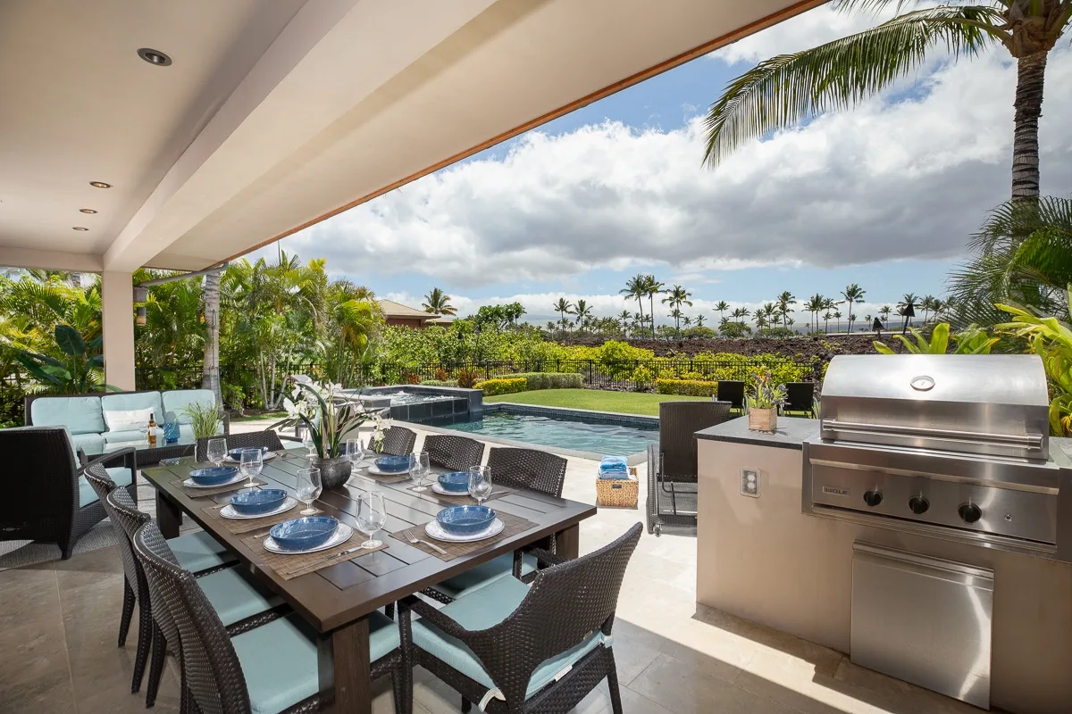 A covered outdoor dining area overlooks a pool and tropical landscaping.