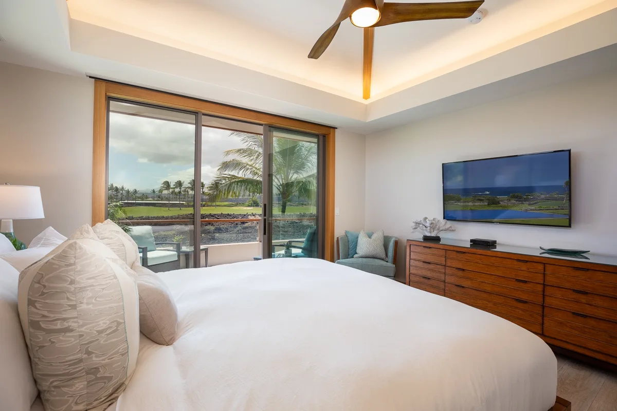 Un dormitorio con una cama grande, puertas corredizas de vidrio y un televisor en la pared.