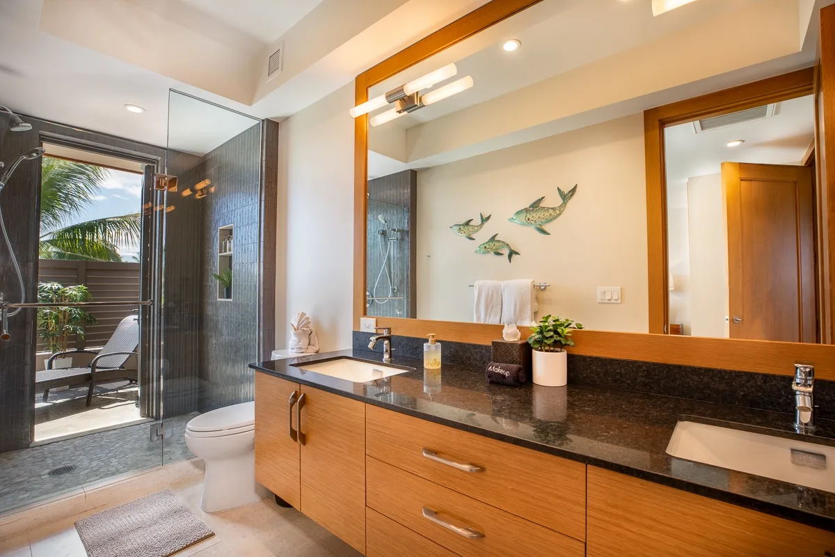 Un baño con un tocador largo y una ducha de vidrio junto a un balcón exterior.