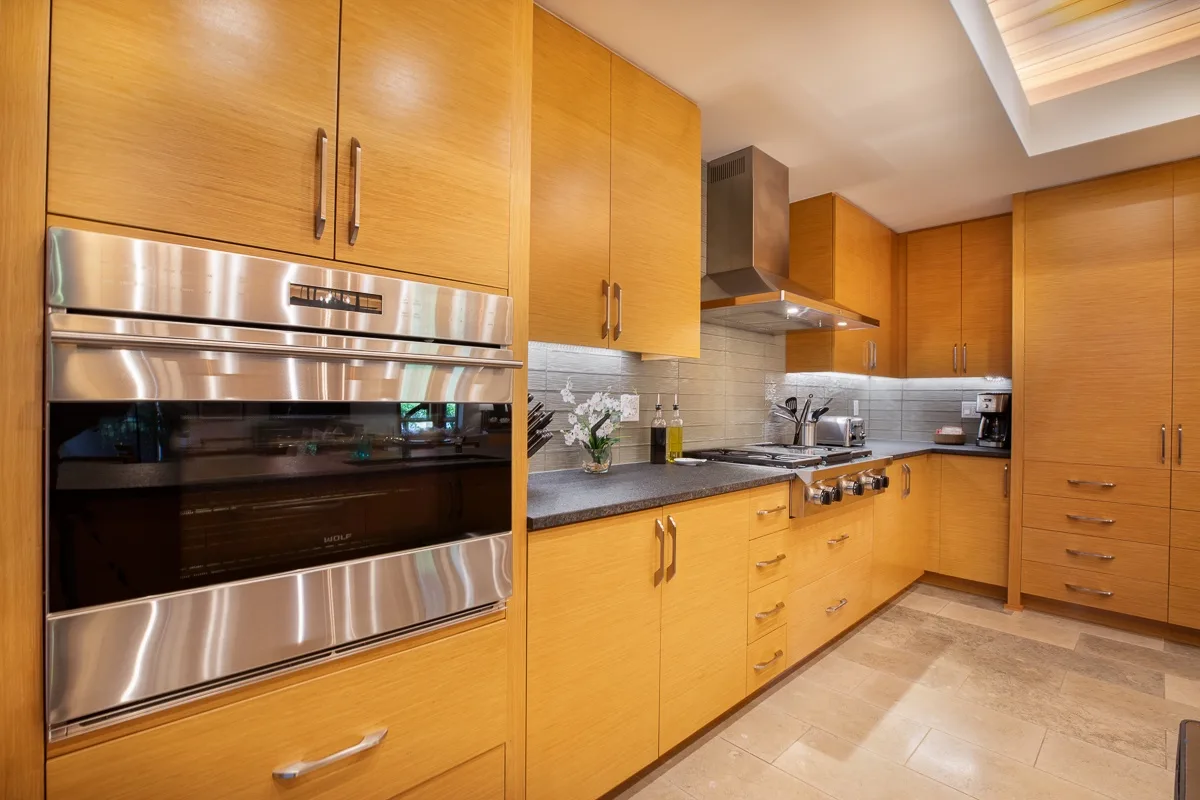 Una cocina con gabinetes de madera, electrodomésticos de acero inoxidable y una zona de cocción.