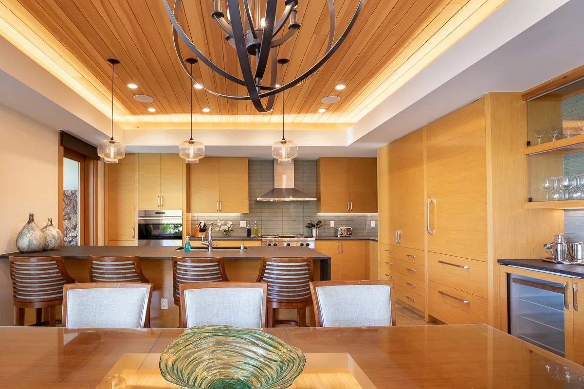 Una cocina y comedor con gabinetes de madera y una barra larga.
