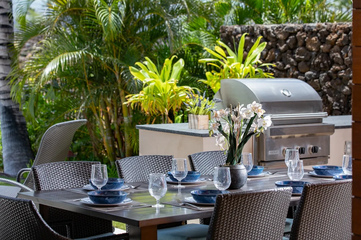 Un comedor al aire libre con la mesa puesta junto a una parrilla empotrada.