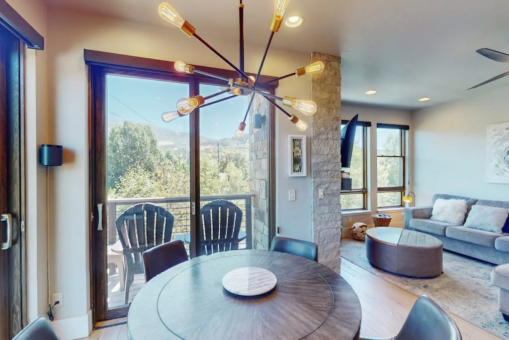 A dining area opens onto a living room with large windows.