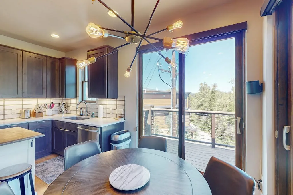 A kitchen and dining area opens onto a balcony through large glass doors.