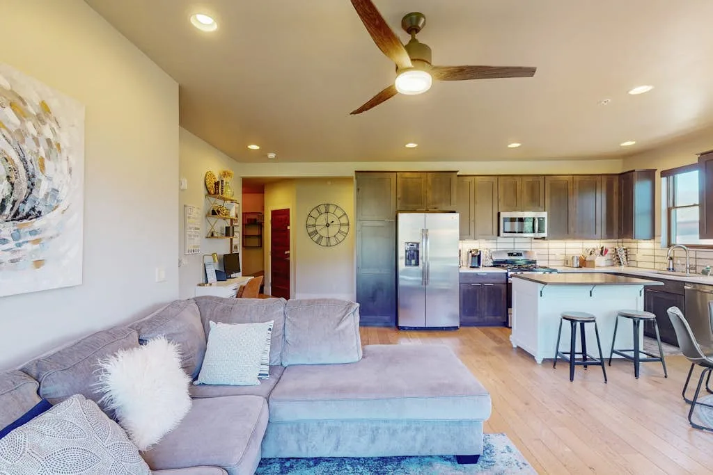 An open-plan living room and kitchen with a sectional sofa and breakfast bar.