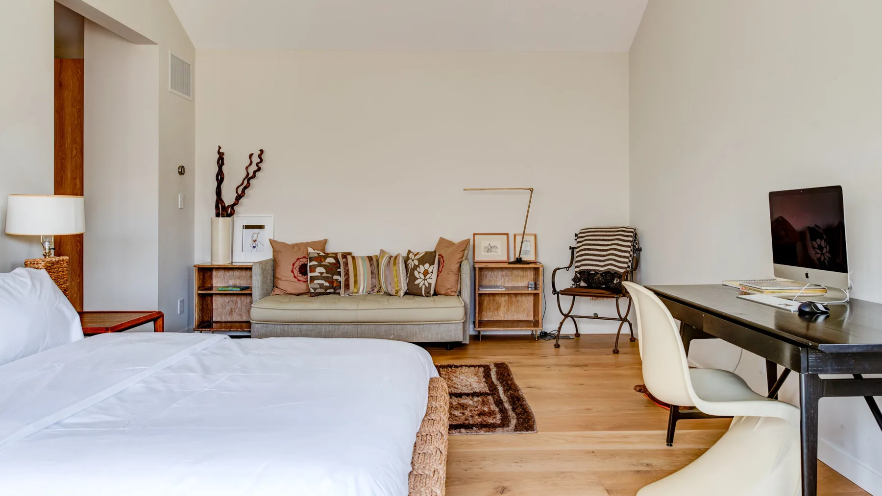 A bedroom with a bed, a seating area, and a desk.