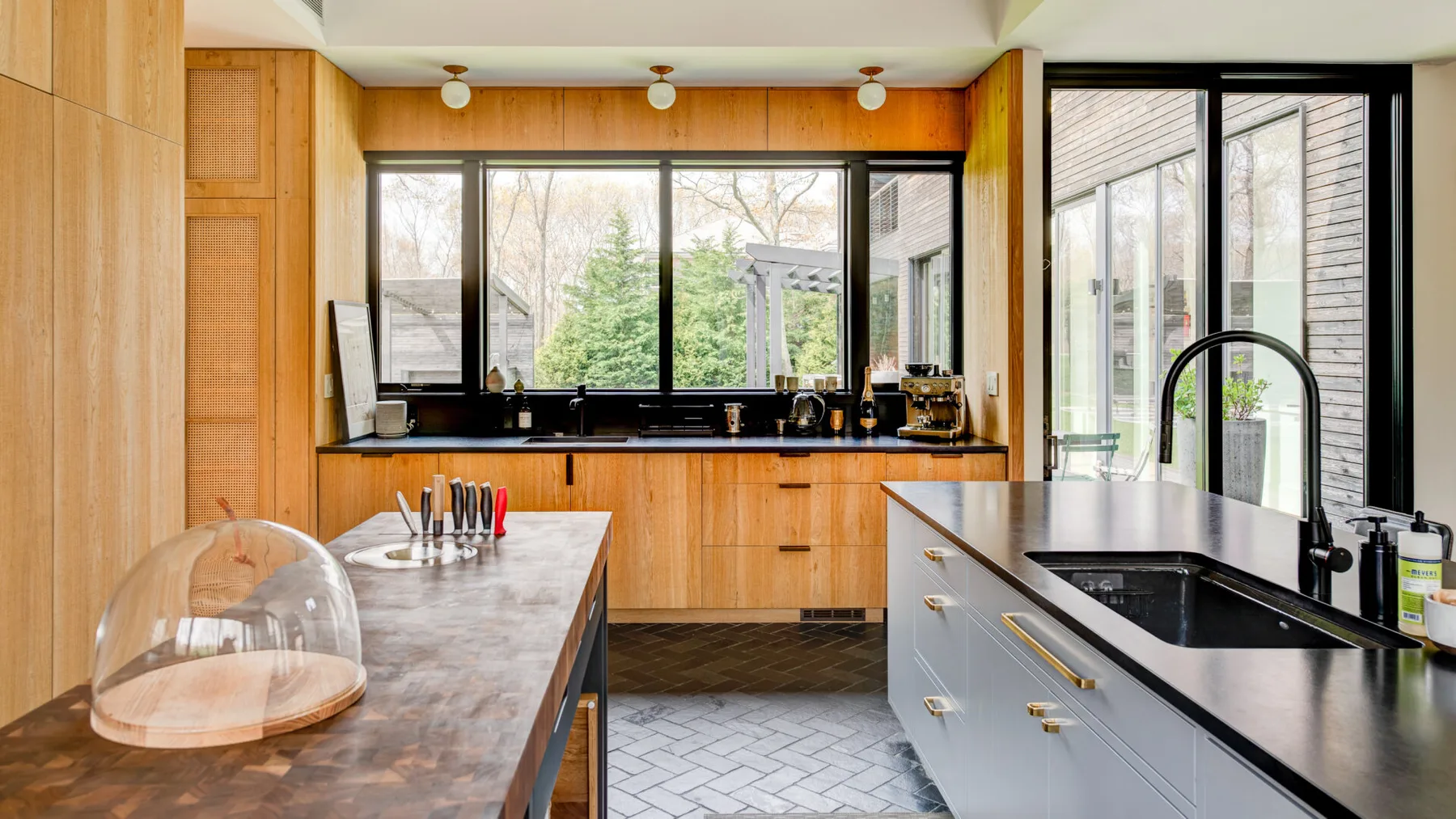 A bright kitchen with wooden cabinets, large windows, and a central island.