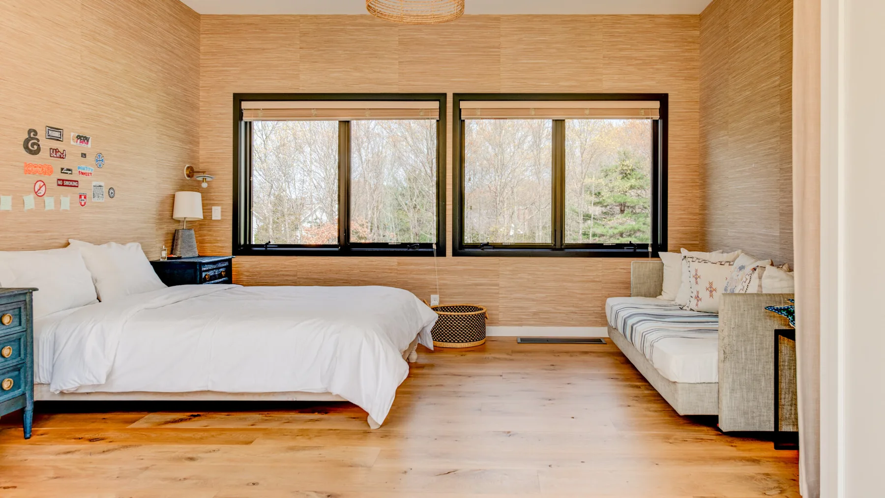 A bedroom with a large bed, a seating area, and wide windows.