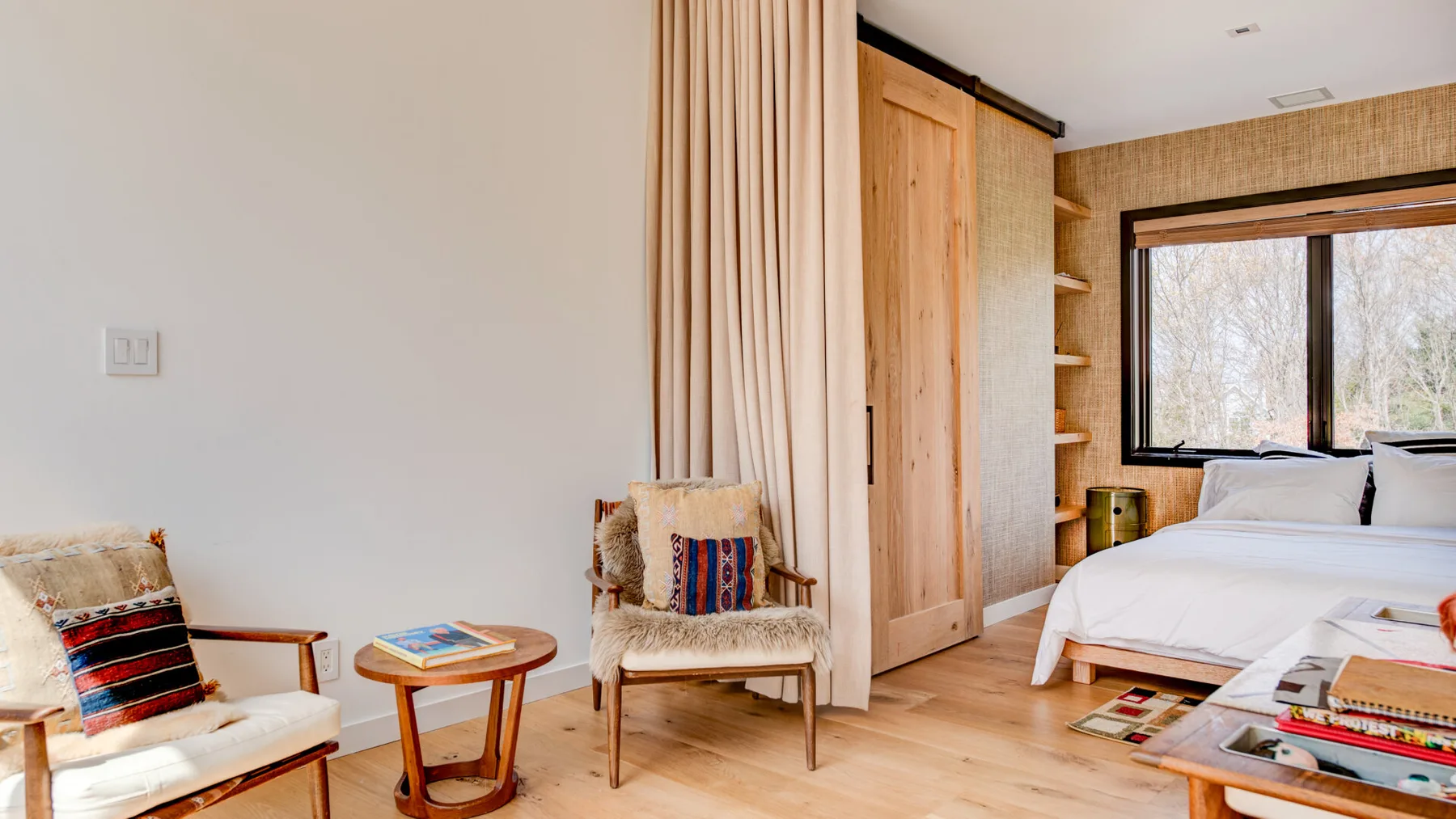 A bedroom with a bed, two armchairs, and a small round table.