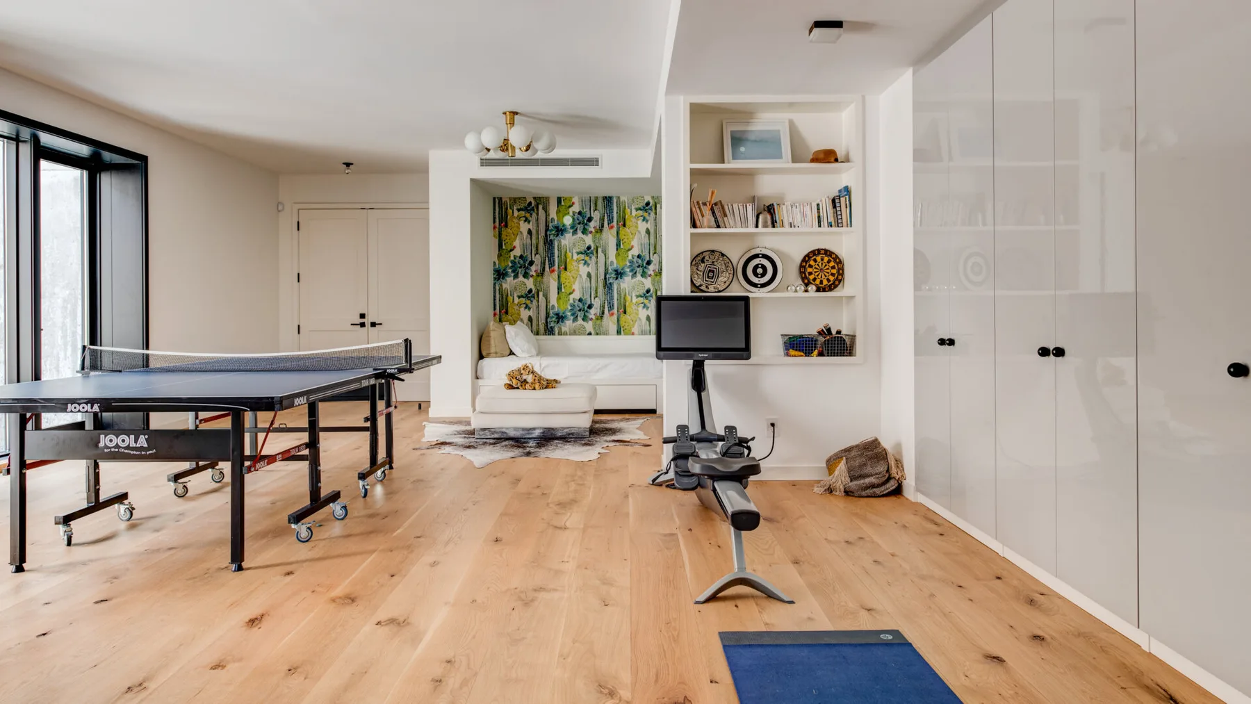 A bright multipurpose room has a table tennis table and a small seating area.