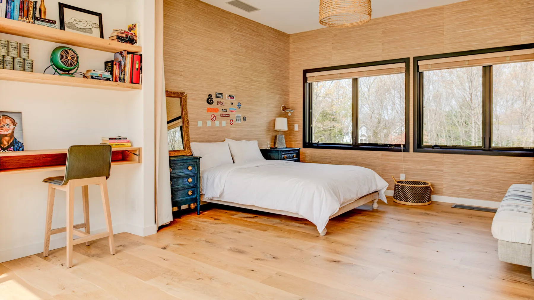 A bright bedroom with a white bed, desk, and large windows.