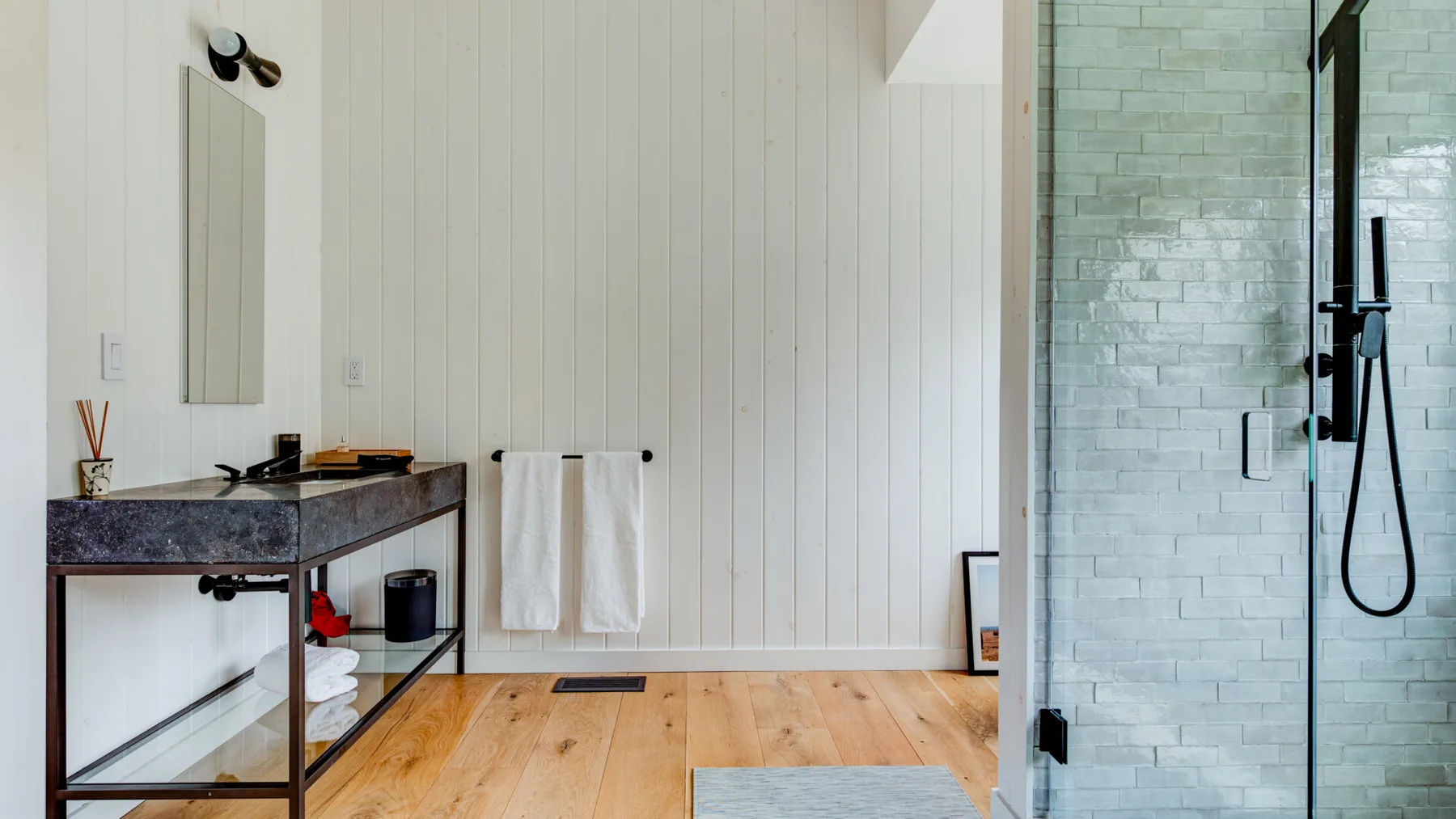 A bathroom with a vanity, towels, and a glass shower.