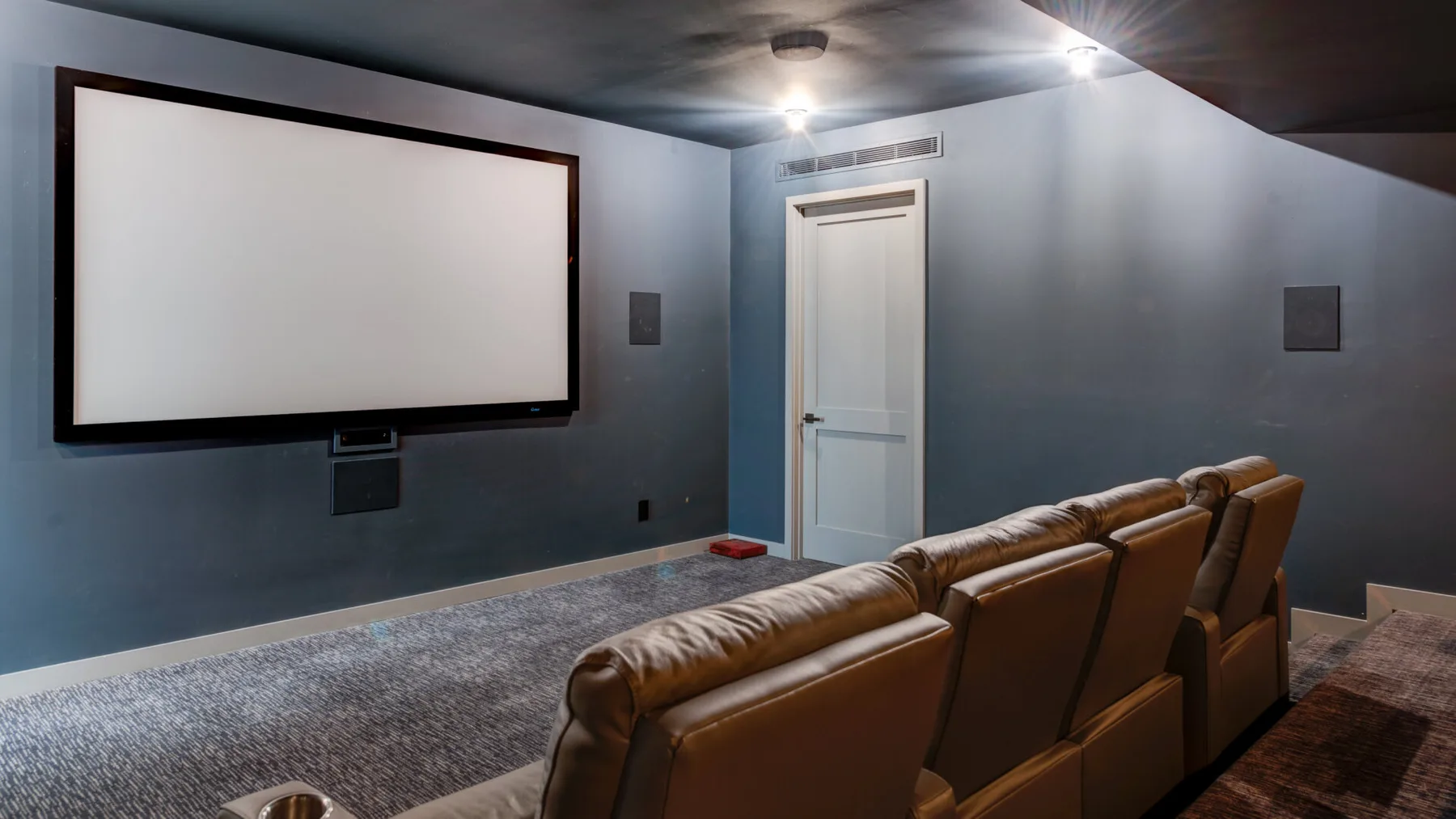 A home theater room with a large projection screen and rows of seating.