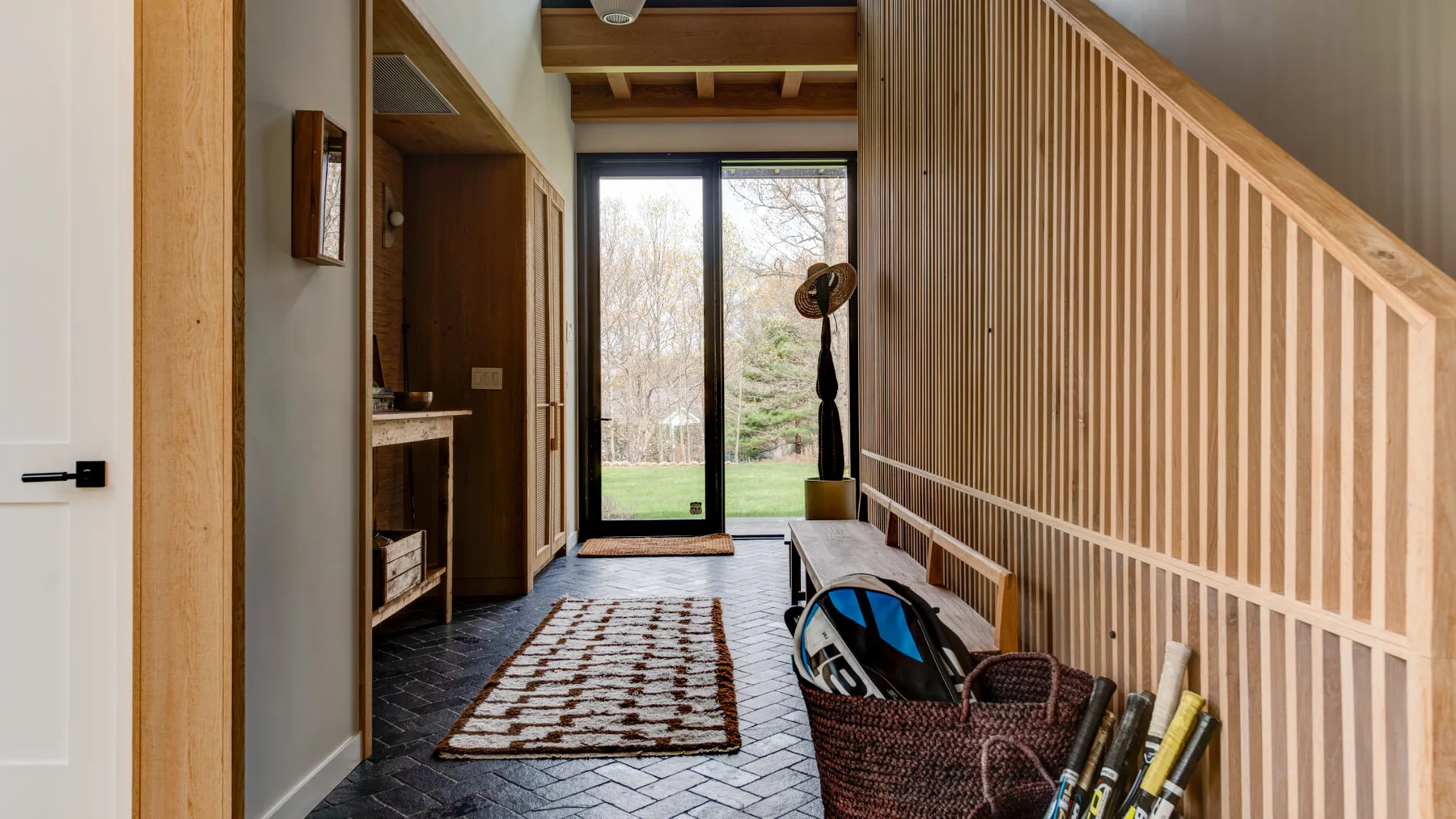 A wood-paneled hallway with a patterned rug and a large window at the end.