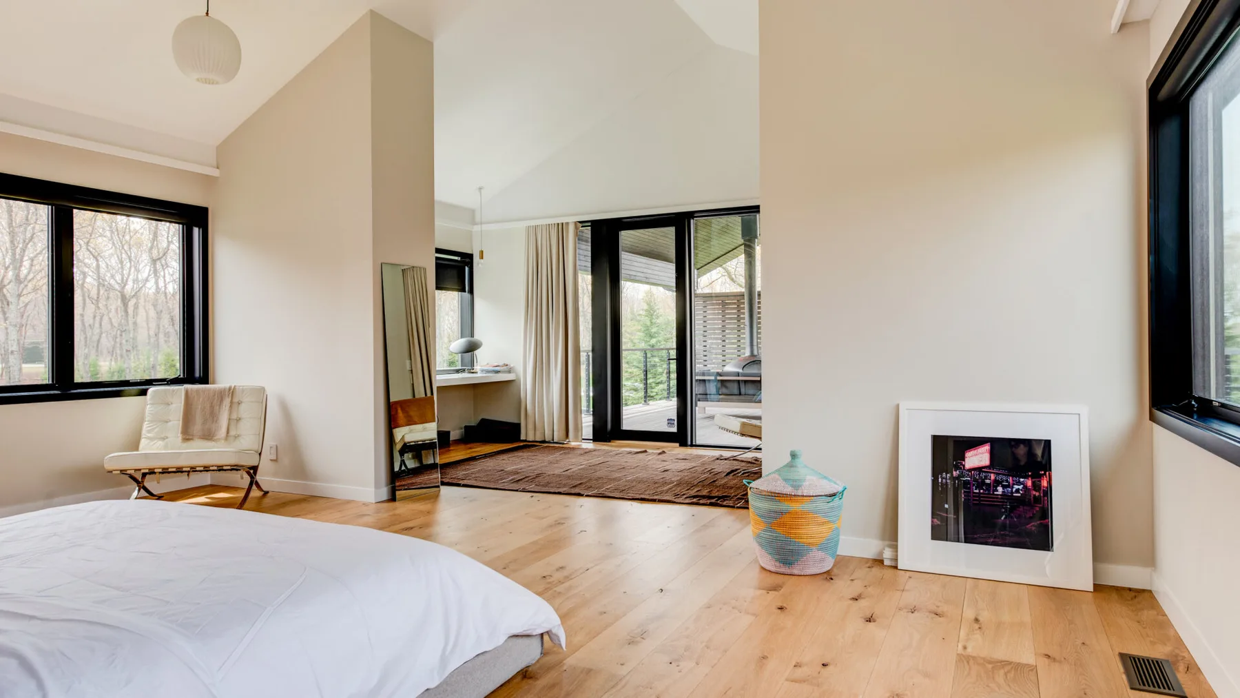 A bright bedroom opens onto a sitting area with large windows and glass doors.