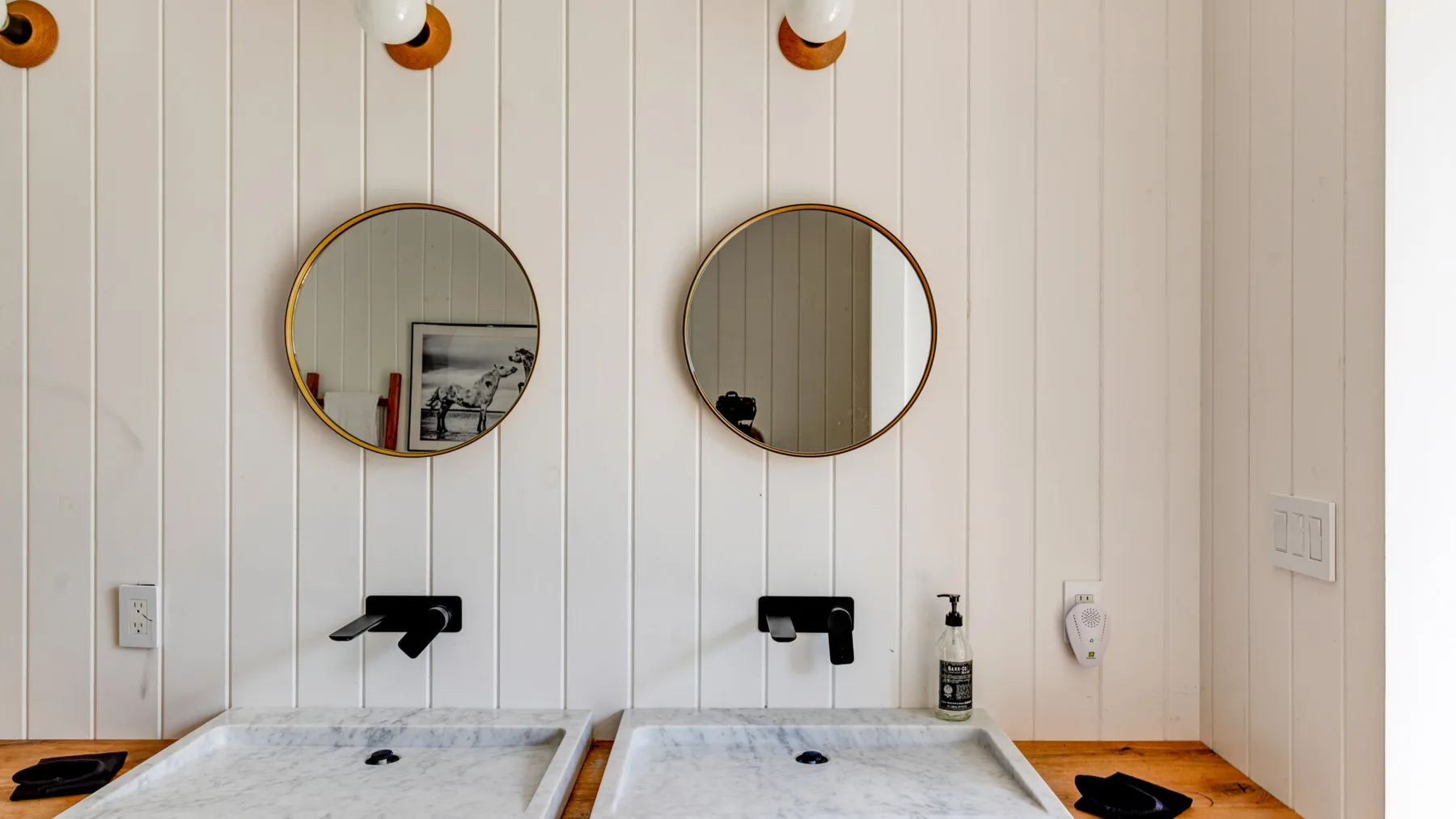 A bathroom vanity with two round mirrors and sinks.