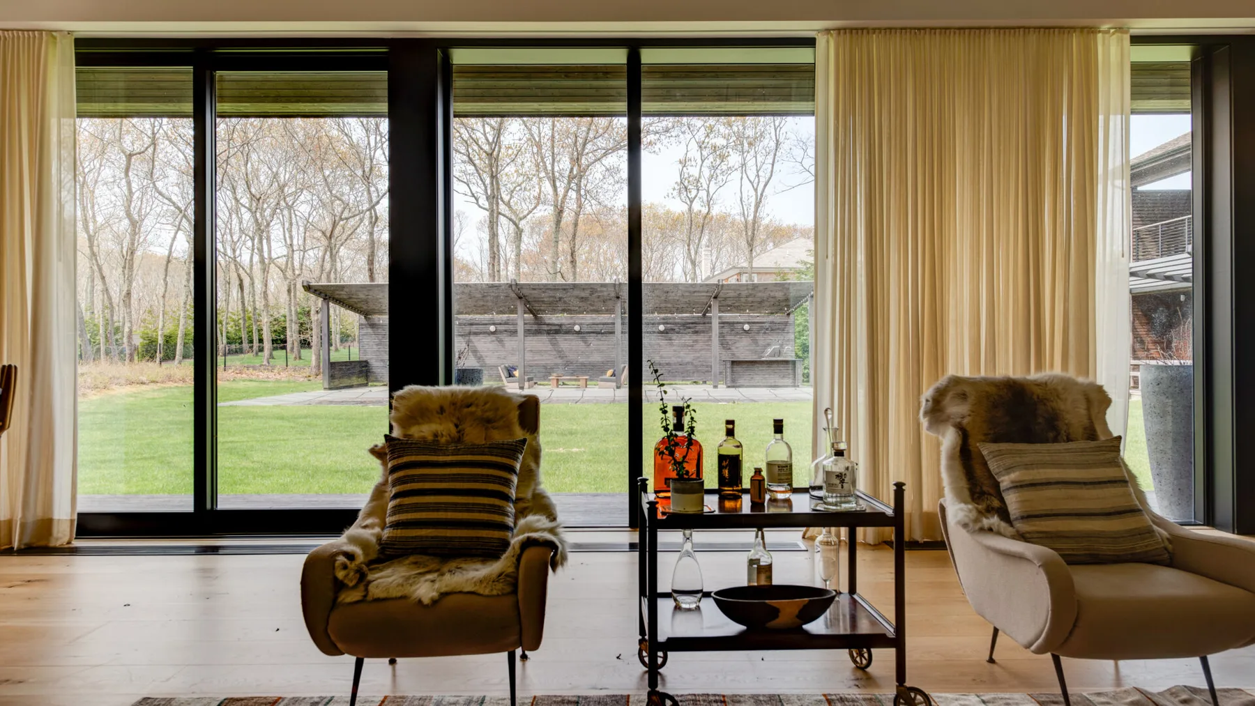 A living room with seating beside large windows overlooking a green lawn.