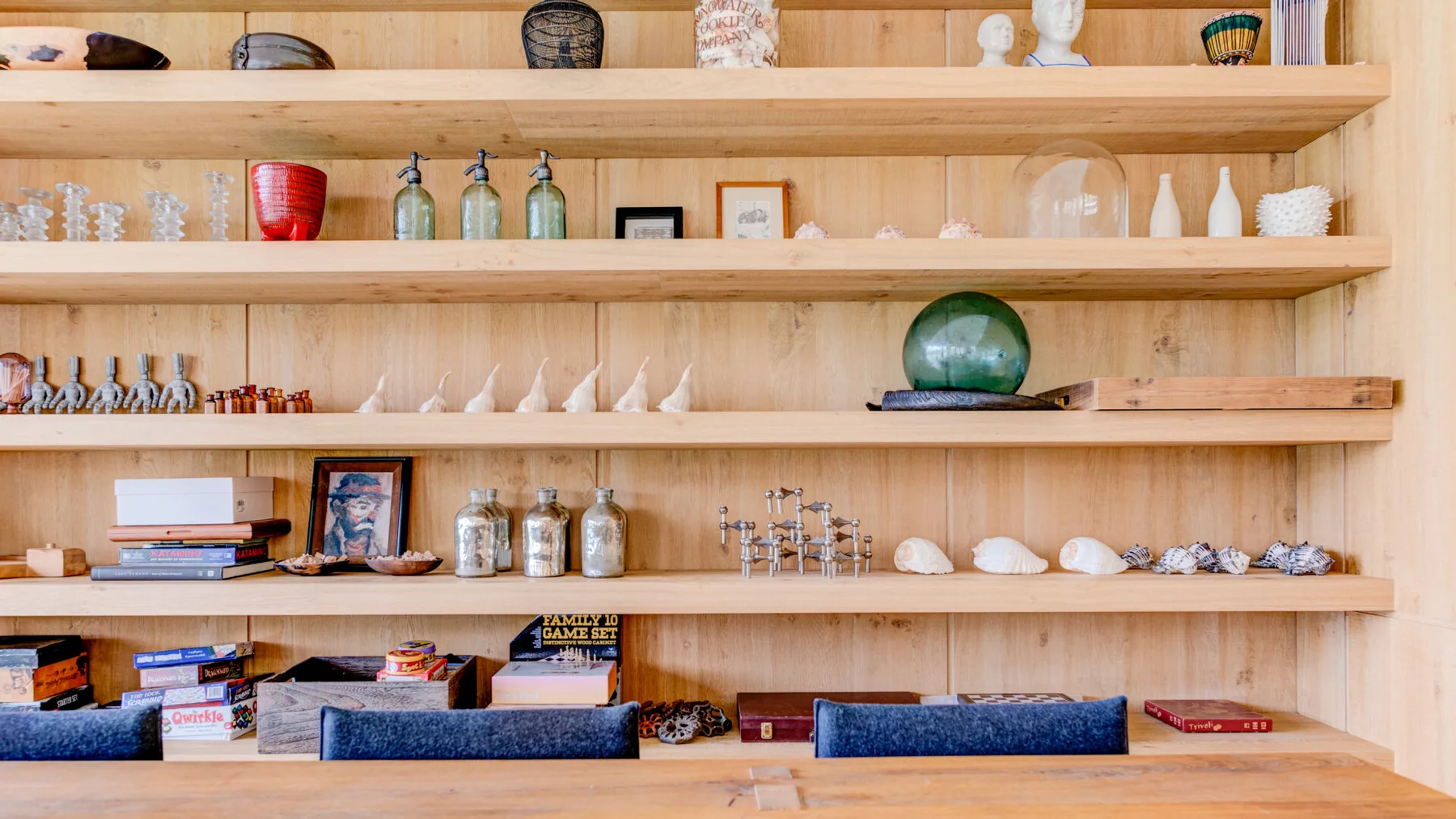 Wooden display shelves hold decorative glassware, ceramics, books, and small objects.