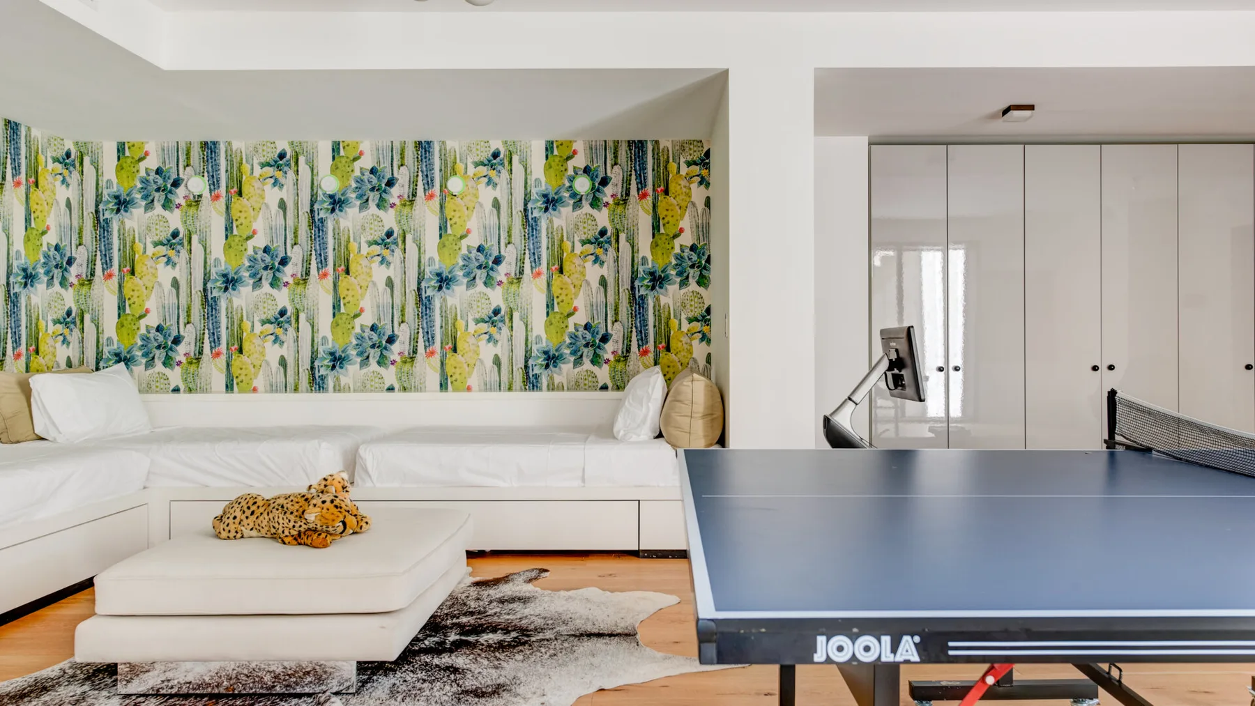 A bright living room with white seating and a table tennis table.