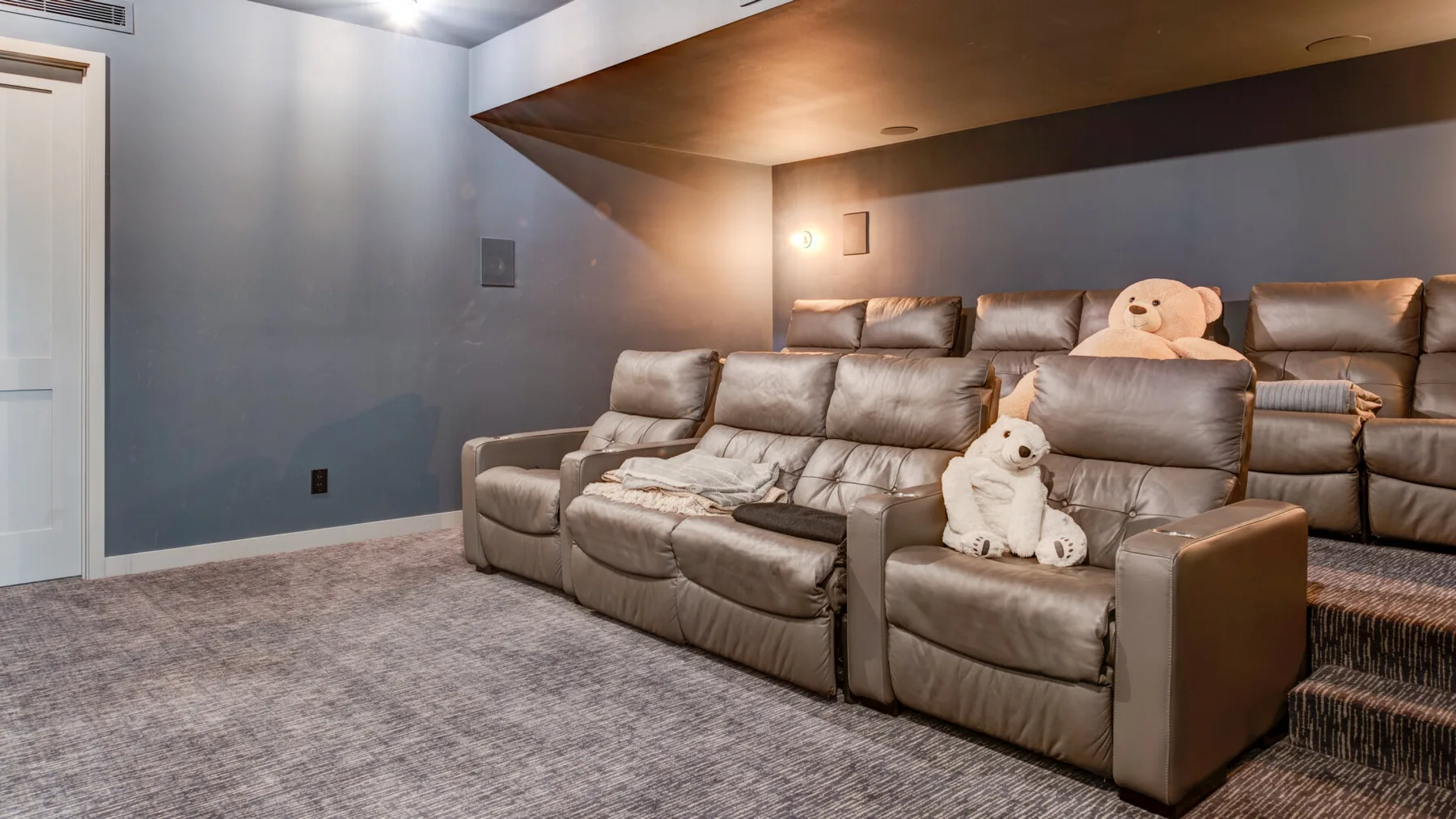 A home theater seating area with reclining seats and a small dog.