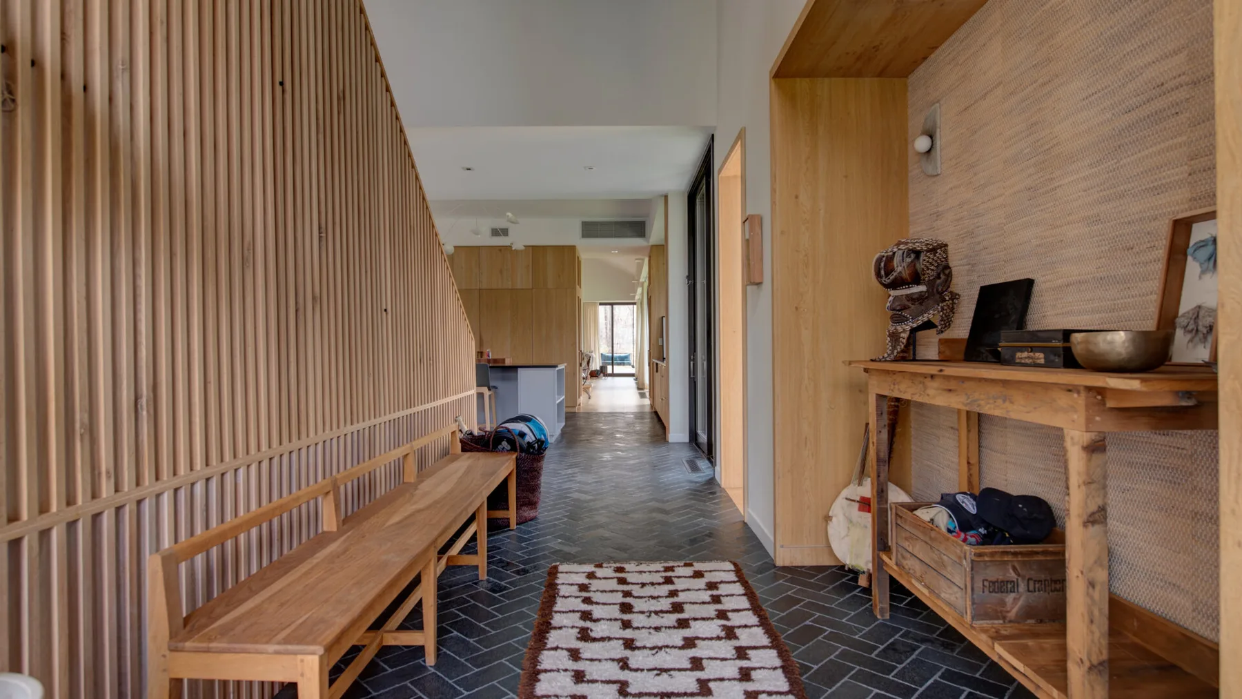A hallway with a long wooden bench and a shelving unit along the wall.