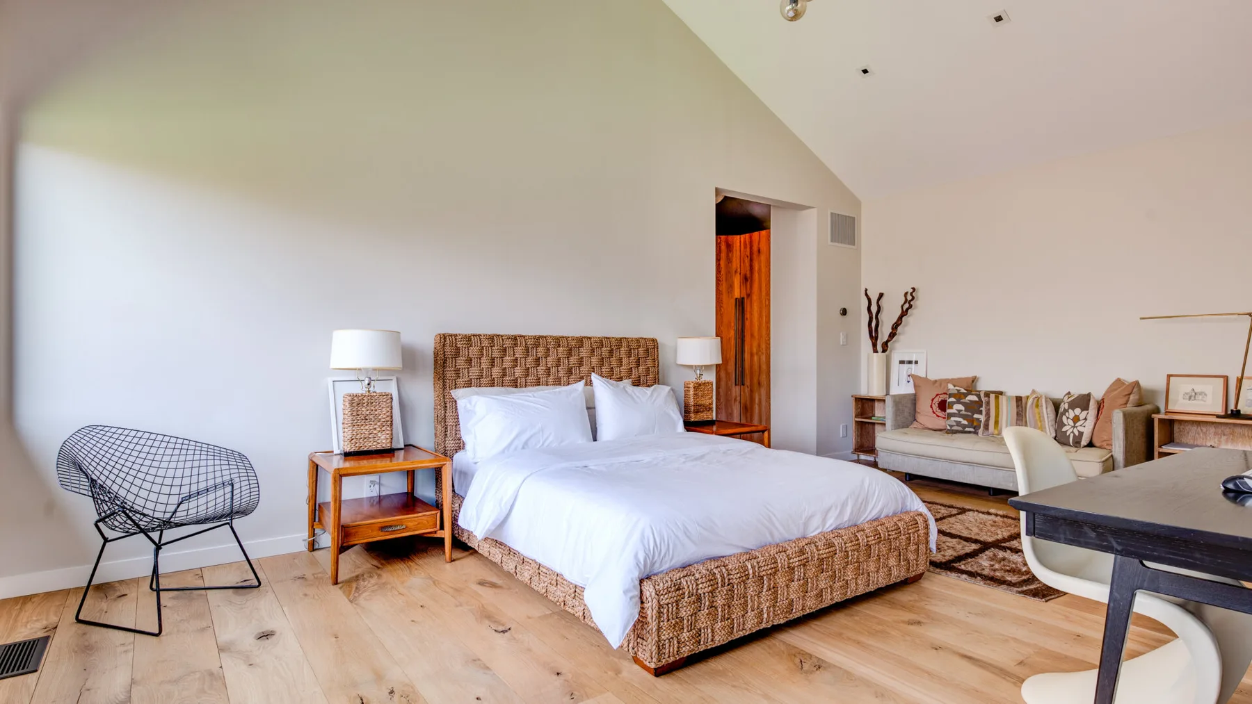 A bedroom with a bed, bedside tables, and a seating area.