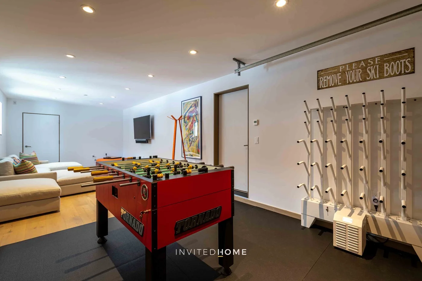 Una sala de juegos tiene un futbolín rojo y soportes para esquís.