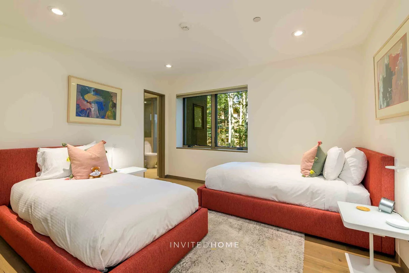 Un dormitorio con dos camas, una ventana y cuadros enmarcados.