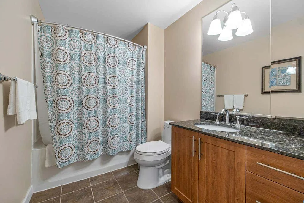 Un baño con una cortina de ducha estampada y un tocador de madera.
