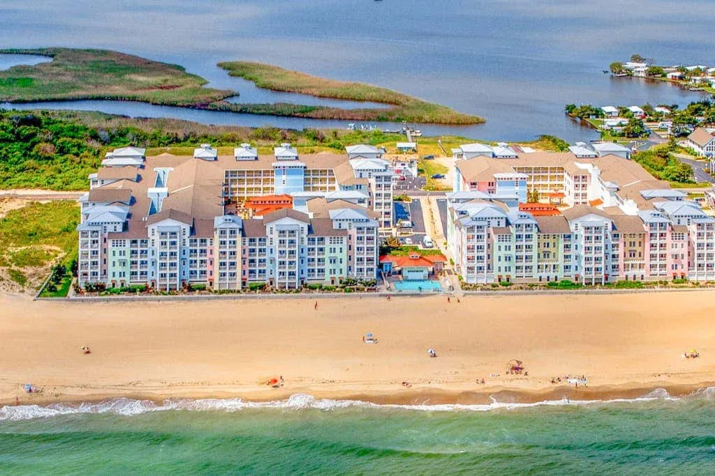 Vista aérea de edificios junto a la playa, una costa arenosa y humedales.